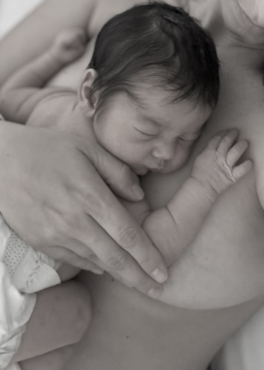 Recién nacido durmiendo piel con piel sobre el pecho de su mamá, en blanco y negro